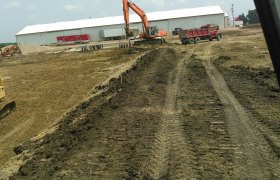 Excavator removing excess aggregate from a worksite