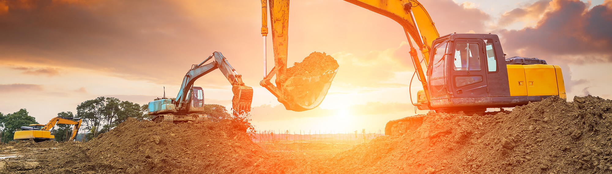 Number of excavators digging at sunset