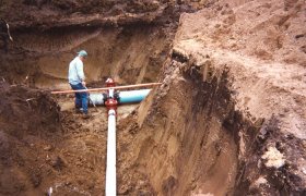 Crew member standing in a trench at the junction point of underground water pipes