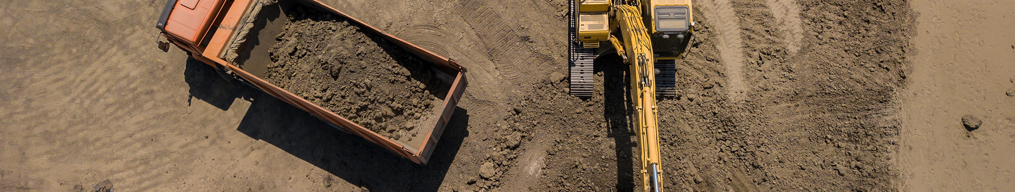 Aerial photo looking overhead at an excavator filling a dump truck